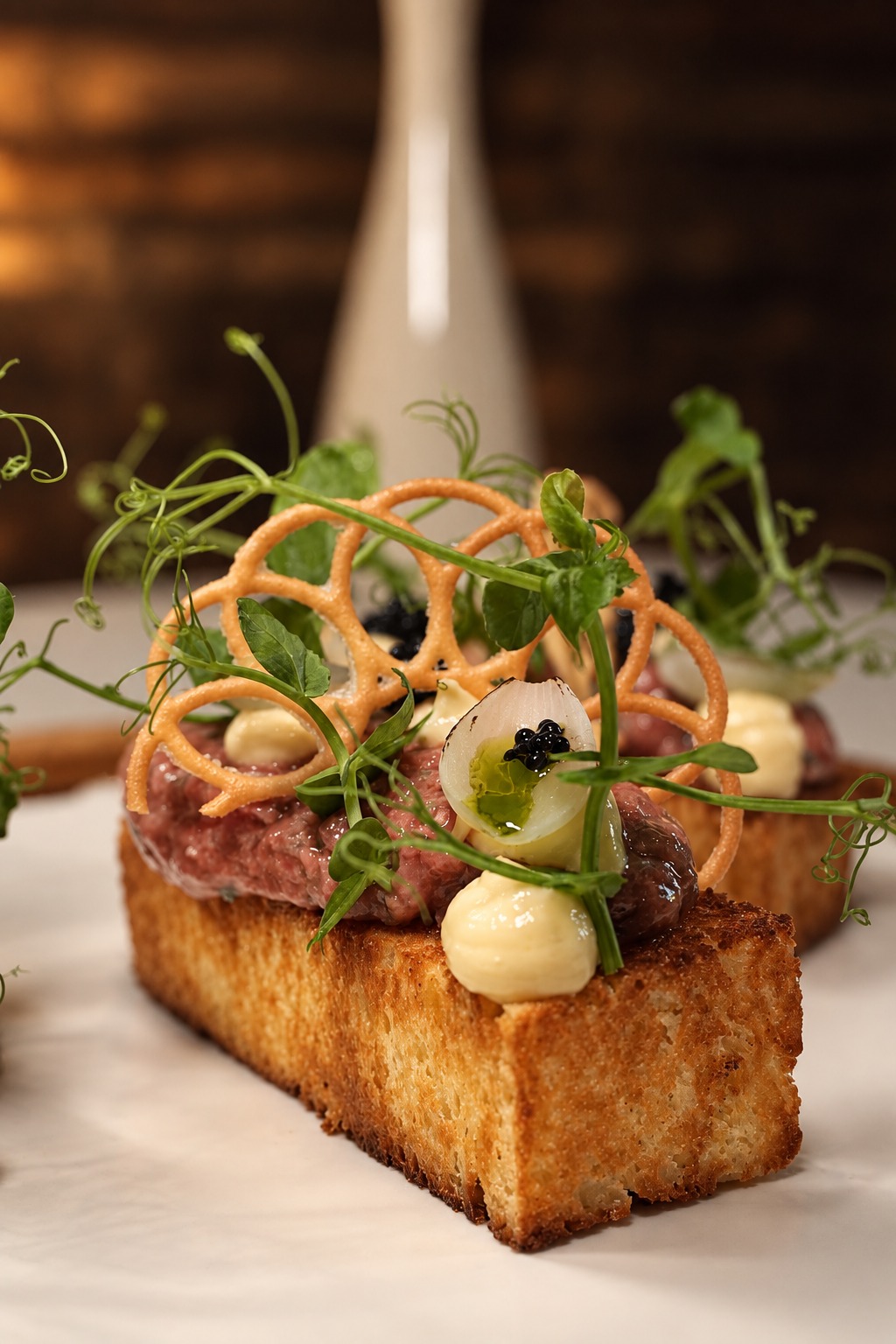 A gourmet toast at Saaser-Stube, topped with fresh herbs and delicate crisp decorations.